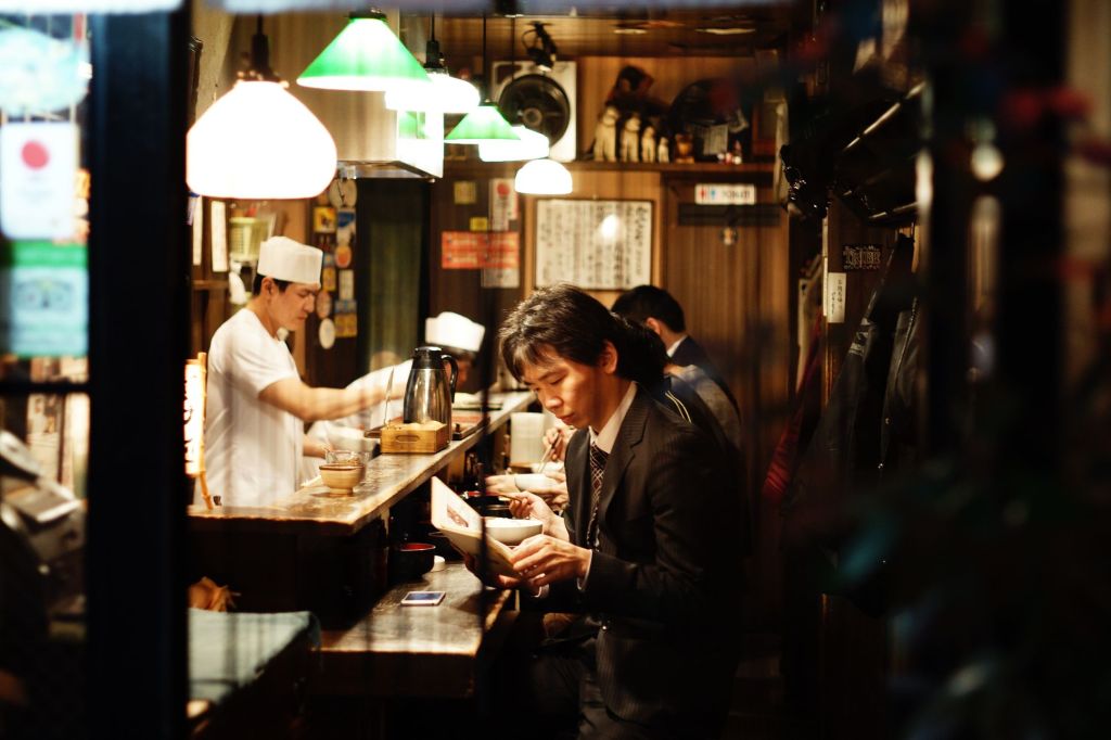 Customer looking at a menu in a restaurant in Japan with the waiter.